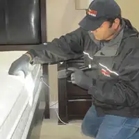 Bed bug inspection technician checking a mattress and bed frame for signs of infestation in Sterling Heights, MI