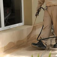 General pest control technician spraying exterior perimeter around a home in Sterling Heights, MI