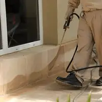 General pest control technician spraying exterior perimeter around a home in Sterling Heights, MI