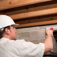 Termite inspection technician checking a basement wall and framing for termite activity in Sterling Heights, MI