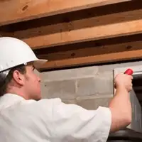 Termite inspection technician checking a basement wall and framing for termite activity in Sterling Heights, MI